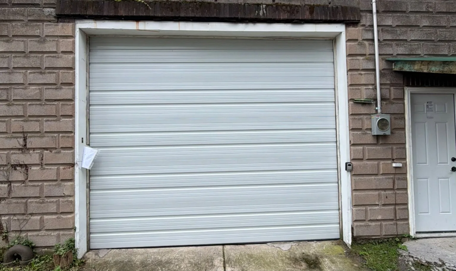 White replacement garage door installed in a brick building, exterior view